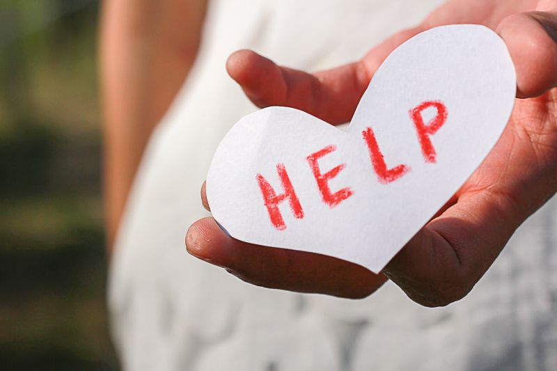 caregiver holding a heart with "help" on it