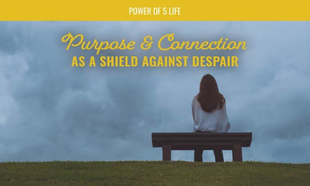 woman sitting on a bench looking out over a grey sky - a blog post about purpose and connection for depression and Suicide Awareness Month