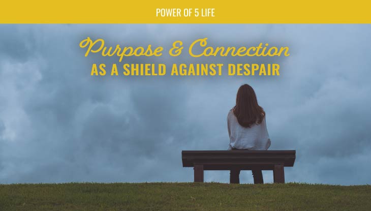 woman sitting on a bench looking out over a grey sky - a blog post about purpose and connection for depression and Suicide Awareness Month